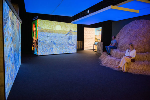 Visitors enjoy Van Gogh's paintings by sitting on a pile of wheat straw during the ongoing interactive show, Meet Vincent Van Gogh. (Photo provided to China Daily)
