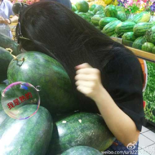 A photo posted by a Sina Weibo user shows her listening to the sound from a watermelon. (Photo/Sina Weibo)