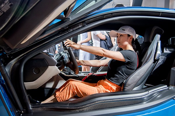 A woman checks out a BMW electric car during a recent NEV fair in Nanjing. Some makers of electric cars have cooperated with property developers to install charging stations at residential areas and office buildings. (Photo provided to China Daily)