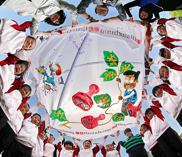 Primary school students and officials in Qinhuangdao, Hebei province, display a painting during an activity in May to promote clean politics and the fight against corruption. Cao Jianxiong / For China Daily