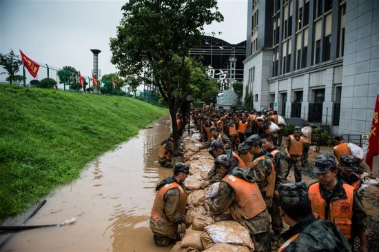 Rescuers reinforce a temporary dyke in Shuren Middle School in Nanjing, capital of east China's Jiangsu Province, July 4, 2016. A section of the embankment of Yangtze River near the school was found continuing leakage Monday morning, and a temporary dyke was built to stop flood water. (Xinhua/Li Xiang) 