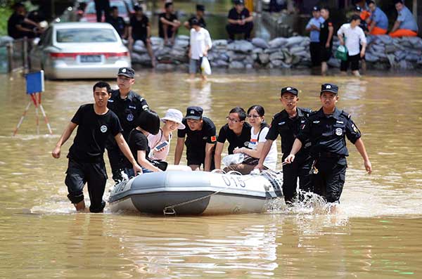 Police officers help residents in Nanjing, Jiangsu province, to use a rubber dinghy after some areas were flooded on Thursday.(Cui Xiao / For China Daily)