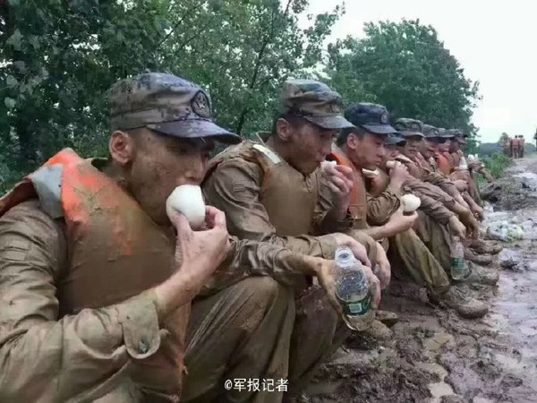 Xie Yongfu, a PLA soldier, eats a steamed bun during the flood relief work in Hubei province, on July 4, 2016. (Photo/Weibo)