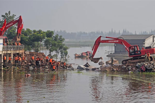 Excavators work at the plugged dike breach in Huarong County, central China's Hunan Province, July 12, 2016. The dike breach in Huarong was plugged after two days of rescue work. (Photo/Xinhua)