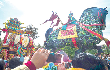 Visitors take pictures using mobile phones while a performer dressed as a Chinese traditional nomadic hero joins a parade of floats at Shanghai Disney Resort. (Provided to China Daily)