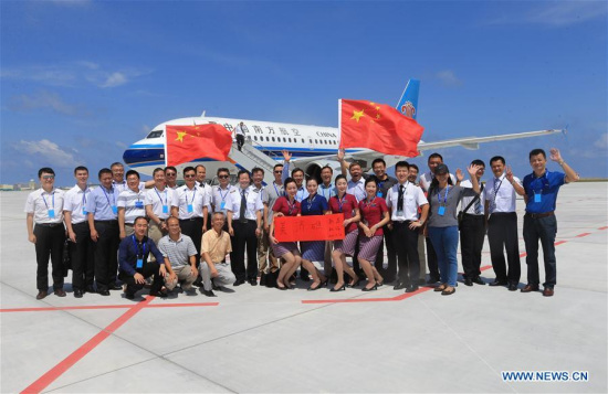 People pose for a group photo after a passenger jet of China Southern Airlines landing at the airport on Meiji Reef, July 13, 2016. (Xinhua/Xing Guangli)