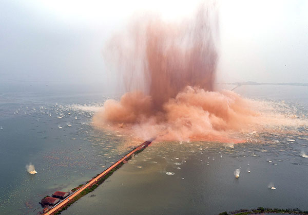 The dike that turned Liangzi Lake into two lakes 37 years ago is destroyed in a controlled explosion in Wuhan, Hubei province, on Thursday. HU JIUSI/CHINA DAILY