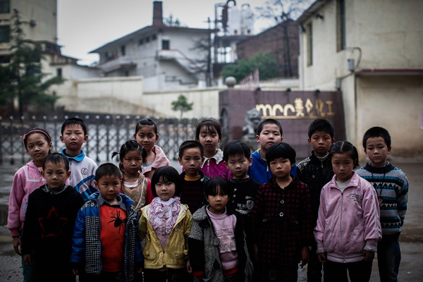 Children who have excessive bloodlead levels stand in front of Hengyang Meilun Chemical Pigment Co in Hengdong county, Hunan province, in April 2014.(YANG YI/CHINA DAILY)