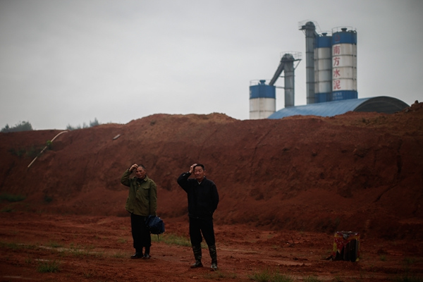 Two villagers stand in front of a cement plant in Hengdong county in 2014.(YANG YI/CHINA DAILY)