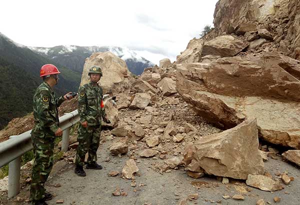 Armed police officers check a landslide site at a section of highway innMarkamcounty in the Tibet autonomous region on Thursday. The landslide was the result of rain. Tan Zeyang / Xinhua