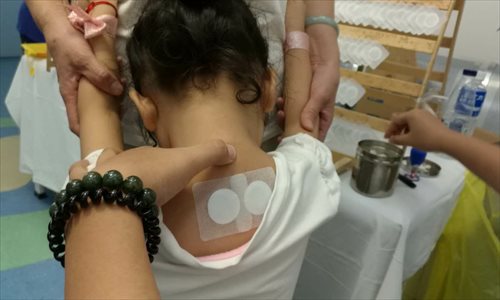 Employees at the Beijing Hospital of Traditional Chinese Medicine (TCM) apply sanfutie (medicinal patches) to visitors on July 17, which saw the start of ��dog days��, hottest days of summer, this year. The traditional treatment is used to help prevent and cure chronic respiratory symptoms such as inflammation of the trachea and sore throat. Photo: Wu Gang/GT