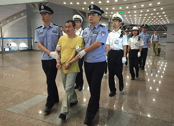 A smuggling suspect surnamed Huang is escorted back to China on Sunday after being in Peru for 18 years. CAI YANHONG/CHINA DAILY