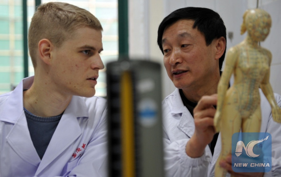 Florian Paillard (L) listens as his tutor Cai Shengchao explains the human's meridian system at the Acupuncture and Moxibustion Hospital of Anhui University of Traditional Chinese Medicine in Hefei, capital of east China's Anhui Province, Feb 13, 2012. (Xinhua/Liu Junxi)
