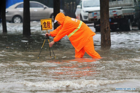 A rescuer places a warning plate on a flooded road in Shijiazhuang, capital of North China's Hebei province, July 19, 2016. Heavy rain afflicted some regions of North China on July 19, causing serious waterlogging in many cities. (Photo/Xinhua)