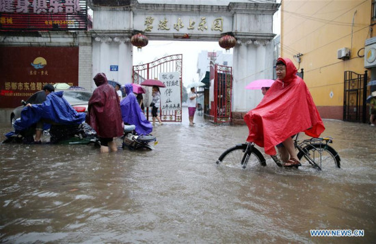 Residents move on a flooded road in Handan, North China's Hebei province, July 19, 2016. Heavy rain afflicted some regions of North China on July 19, causing serious waterlogging in many cities. (Photo/Xinhua)