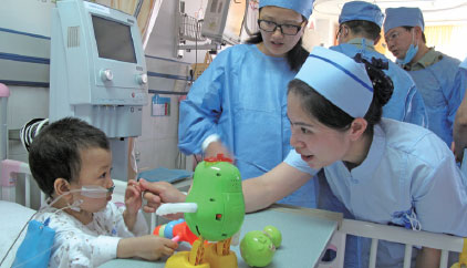 A nurse talks with a child of the Qiong ethnic group, who just had a surgical operation for congenital heart disease, at the Chengdu Military General Hospital. Huang Zhiling / China Daily