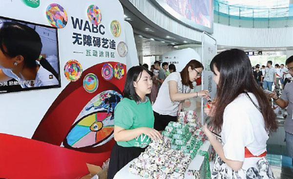 A Tencent employee, and charity supporter, explains to a visitor how to take part in Tencent's program in September, 2015. (Photo provided to China Daily)