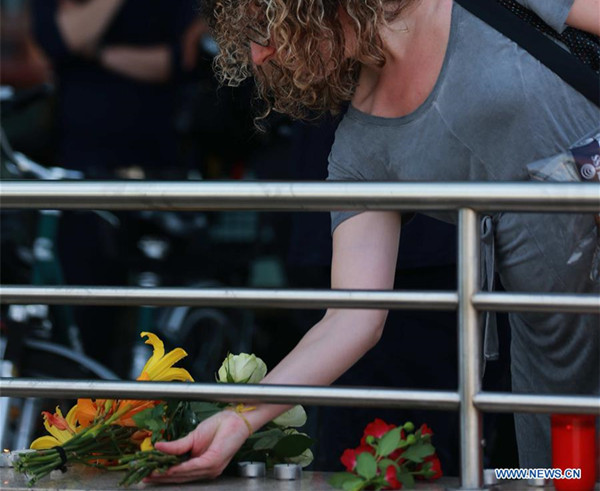 A woman places flowers near the attack scene to show condolence in Munich, Germany, on July 23, 2016. An 18-year-old German-Iranian gunman opened fire in a crowded shopping mall in Munich on Friday evening, killing 10 people and injuring 27. (Xinhua/Luo Huanhuan) 