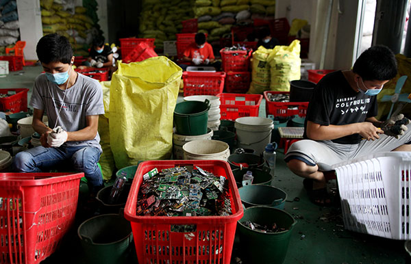 Workers recycle e-waste in Guiyu township, Shantou, on July 12. Guiyu has been nicknamed 'the e-waste capital' by the locals, and almost every family works in the recycling sector. QIU QUANLIN/CHINA DAILY