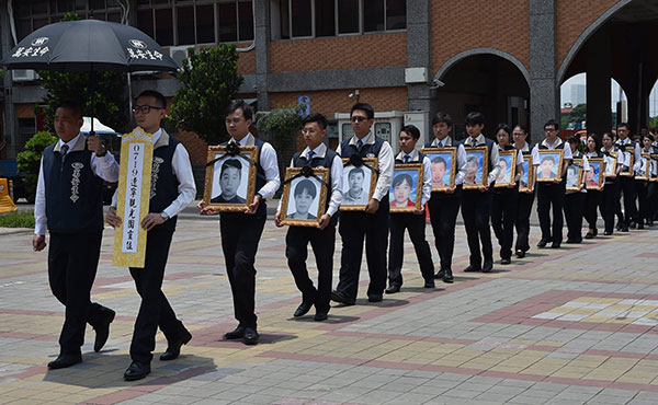 The framed photos of 26 people who died in a tour bus fire in Taiwan on July 19 are escorted to a memorial hall in Taoyuan city on Monday. XU DONGDONG/CHINA NEWS SERVICE