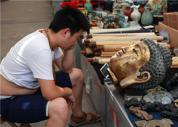 A customerless vendor watches a video on his smartphone.