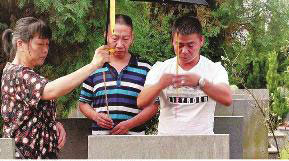 Ma Jianhua (right) and Li Rongfu (middle) pay respect to their deceased parents after going home 44 years later. (Photo/Huashang Daily)