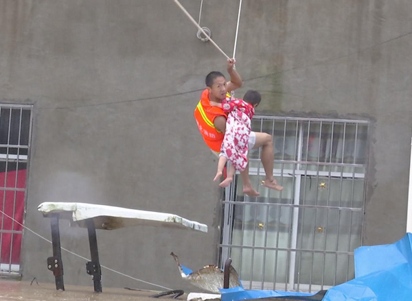 Liu Xiaopeng, a firefighter, uses ropes to rescue a stranded child with the help of comrade in Dawu county, Hubei province, on Friday. (Photo by Wang Jida / For China Daily)