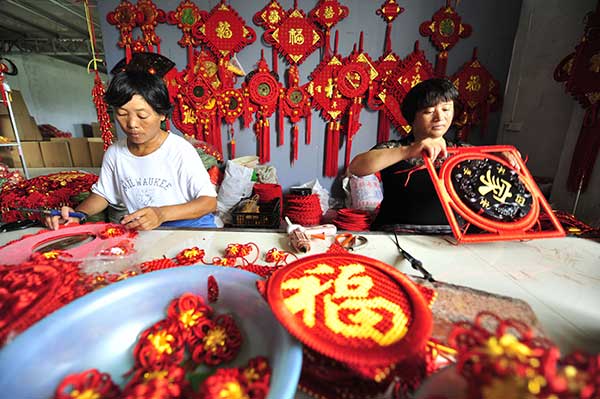 Two women make Chinese knots at the factory owned by entrepreneur Wang Chao at Honghua town in Linyi. (Photo by Lu Peng/Xinhua)
