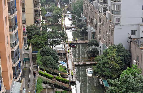 People walk on a 2,000-meter-long wooden platform built as a makeshift bridge at a residential community in Wuhan on July 11, 2016. Rising waters inundated the city and the flooding inconvenienced residents. (Photo/youth.cn) People walk on a 2,000-meter-long wooden platform built as a makeshift bridge at a residential community in Wuhan on July 11, 2016. Rising waters inundated the city and the flooding inconvenienced residents. (Photo/youth.cn)