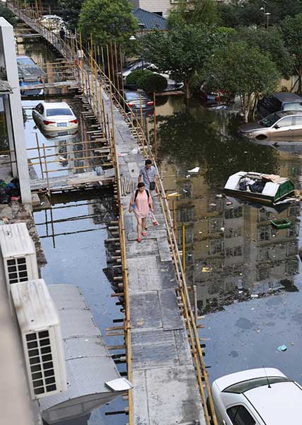 People walk on a 2,000-meter-long wooden platform built as a makeshift bridge at a residential community in Wuhan on July 11, 2016. Rising waters inundated the city and the flooding inconvenienced residents. (Photo/youth.cn)