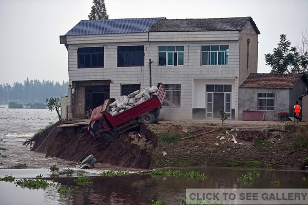 A truck full of big stones falls into the turbulent at the breach of a dike in Huarong county, Central China's Hunan province, on July 10, 2016. (Photo/Xinhua)