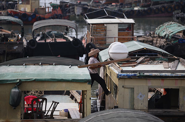 A fisherwoman reinforces her fishing vessel at the Zhapo fishing harbor in Yangjiang, Guangdong province, on Monday as Typhoon Nida headed toward the region. (Photo by ZHANG YOUQIONG/for CHINA DAILY)