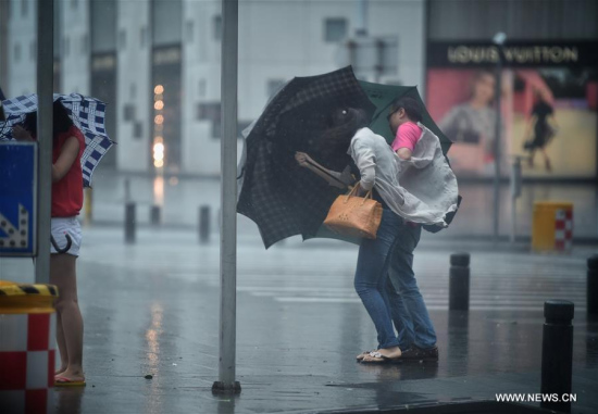 Pedestrians brave strong wind to cross a road in Shenzhen, south China's Guangdong Province, Aug. 2, 2016. (Xinhua/Mao Siqian) 