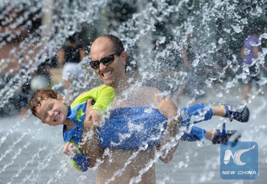 Father and son cooling off in fountain water in Washington D.C., where temperature hits 35 degrees Celsius in June, 2016. (Xinhua Photo)