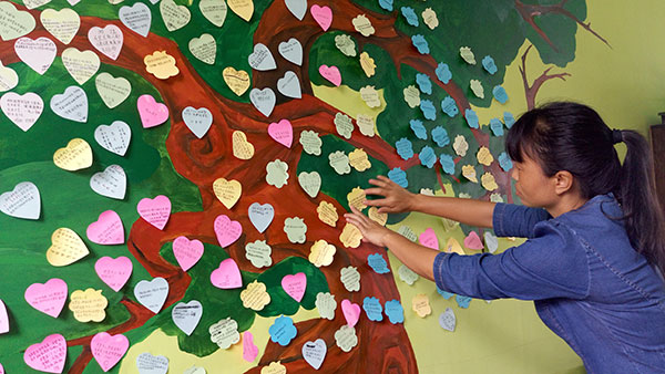A teacher at Yingjiang No 3 High School posts students' love messages in the school's Youth Love Station on June 22. YANG WANLI/CHINA DAILY