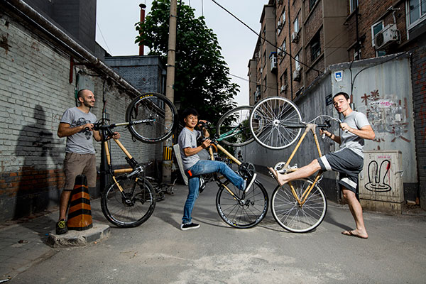 David Wang (right) and two other members of his Bamboo Bicycles Beijing workshop display their bamboo-framed bicycles in Beijing's Langjia hutong.(Photo by Shen Bohan/Xinhua)