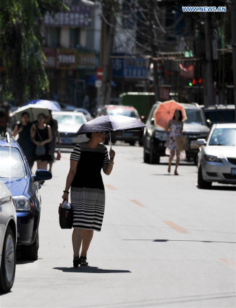A woman holds an umbrella to shield herself from the sun in Hohhot, capital of north China's Inner Mongolia Autonomous Region, Aug. 3, 2016. (Xinhua/Lian Zhen)  