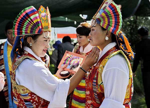 A Tibetan Opera actress helps a cast member apply makeup before a Tibetan Opera competition in Lhasa, capital of the Tibetan autonomous region, on Tuesday. (Zhang Rufeng / Xinhua)