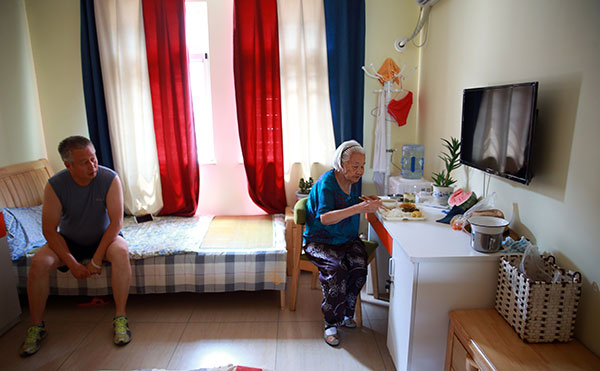 Xu Fengqin, a Puleyuan resident, eats lunch while being watched by her son, who pays regular visits.(Zou Hong/China Daily)