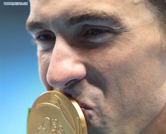 Michael Phelps of the United States of America kisses his medal during the awarding ceremony for the mens 200m butterfly final of swimming at the 2016 Rio Olympic Games in Rio de Janeiro, Brazil, on Aug. 9, 2016. Michael Phelps won the gold medal with 1 minute 53.36 seconds. (Xinhua/Cao Can)