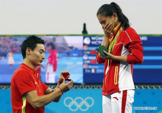 Silver medalist China's He Zi (R) recieves a marriage proposal from China's diver Qin Kai after the awarding ceremony for the women's 3m springboard final of Diving at the 2016 Rio Olympic Games in Rio de Janeiro, Brazil, on Aug. 14, 2016. (Xinhua/Ding Xu)
