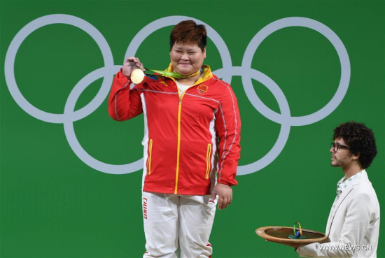 China's Meng Suping shows the gold medal at the awarding ceremony of the women's +75KG weightlifting group A competition at the 2016 Rio Olympic Games in Rio de Janeiro, Brazil, on Aug. 14, 2016. Meng Suping won the gold medal with 307KG. (Photo/Xinhua)