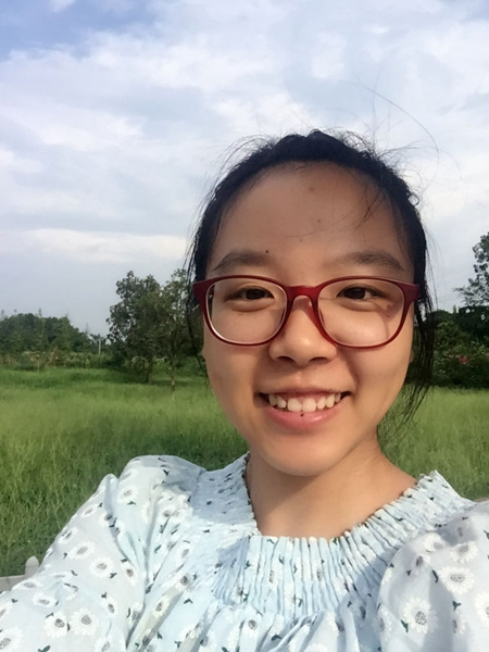 Huang Meihua takes a selfie in a grassy area with a lot of trees in the background. (Photo provided to chinadaily.com.cn)