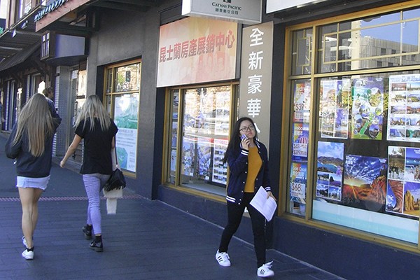 A Chinese student walks past a property trade center in Queensland, Australia. (Photo/China Daily)