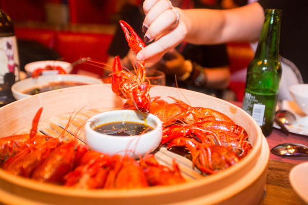 A diner enjoys a popular dish of crayfish, with spicy sauce and seasoning, at a restaurant in Hangzhou, capital of eastern China's Zhejiang province. Xu Kangping / For China Daily