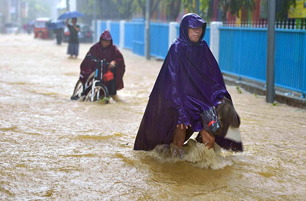 Residents navigate a flooded street in Lingao, Hainan province, after typhoon Dianmu made landfall. (Photo by Fei Yunluo/For China Daily)