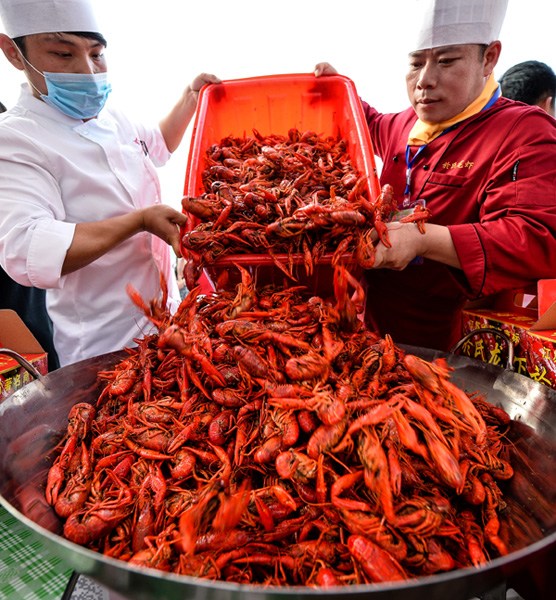 Cooks prepare crayfish for customers. The dish is highly popular in China during Summer time. (Photo/Xinhua)