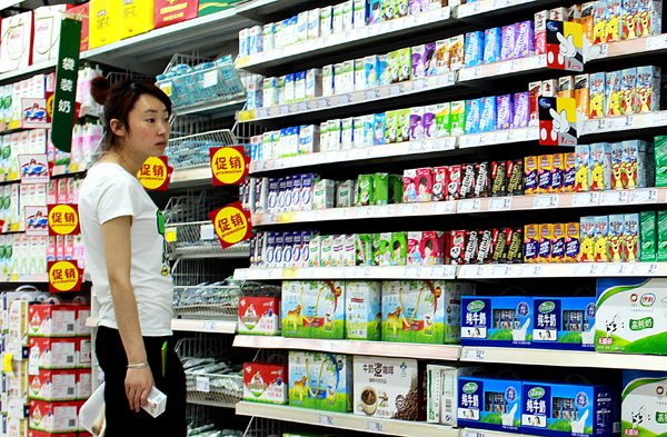 A consumer searches dairy products in a supermarket in Nanjing, Jiangsu province, in June. (Photo by Zhen Huai/For China Daily)