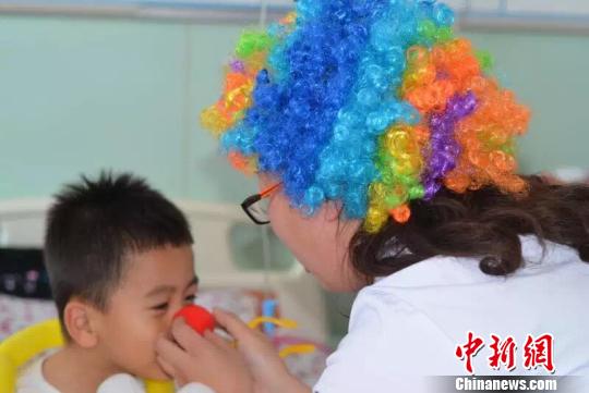 A doctor clown plays with a patient. (Photo/chinanews.com)