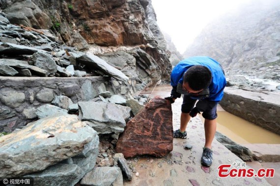 People search for lost cliff paintings as floodwaters recede at the protection zone of the cliff paintings of Helan Mountains in Yinchuan City, Northwest Chinas Ningxia Hui Autonomous Region, Aug. 23, 2016. Dating back to prehistoric times, tens of thousands of cliff paintings have been found across 250 kilometers at the Helan Mountains.(Photo/CFP)